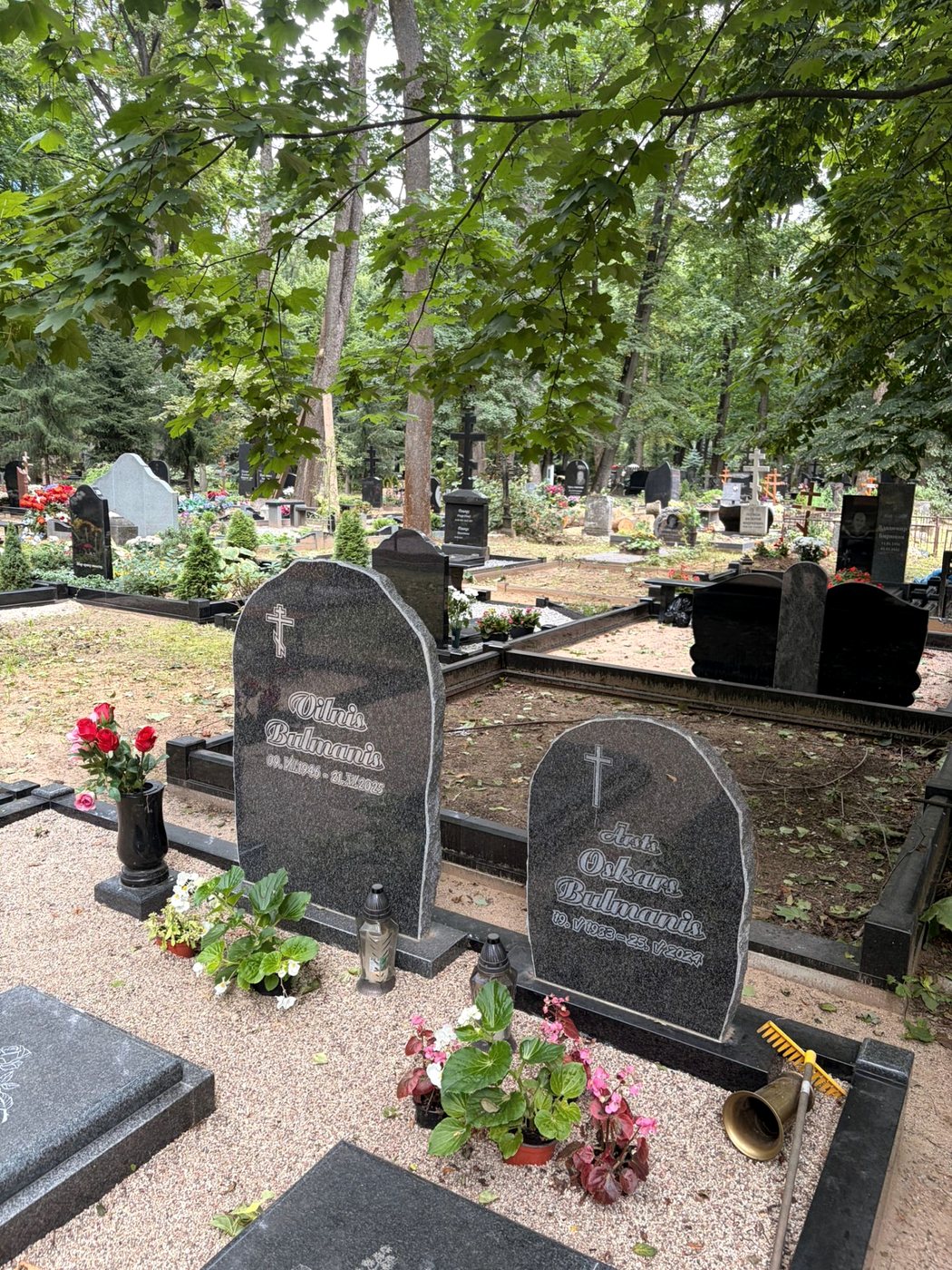 Divi pelēki noapaļoti pieminekļi ar krustiem